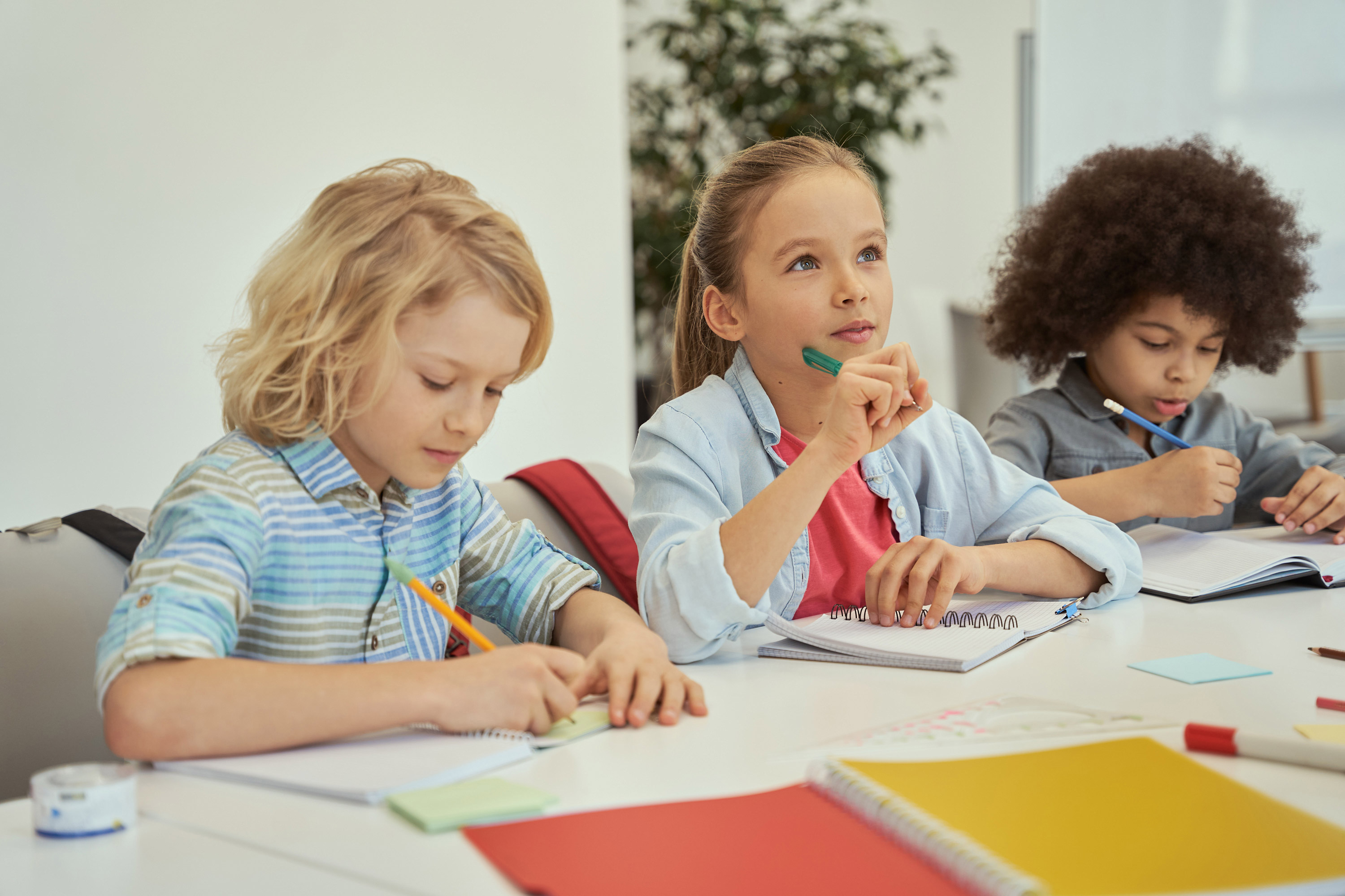© konstantinraketa | freepik.com | Beautiful little girl looking away while listening to teacher kids studying and making notes